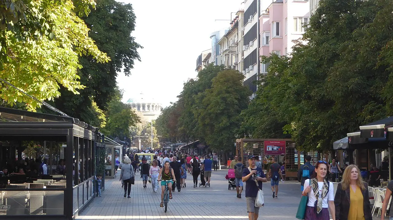 People walking and cycling along the tree-lined pedestrian Vitosha Boulevard in central Sofia, cafe terraces on both sides