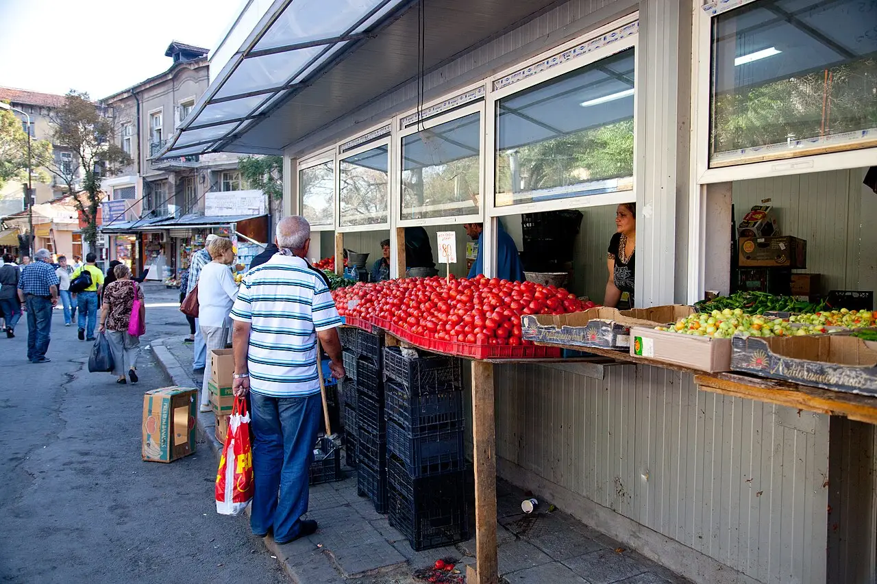 Fruit and vegetable stalls piled high with produce at the Zhenski Pazar market in central Sofia, shoppers browsing between the tables